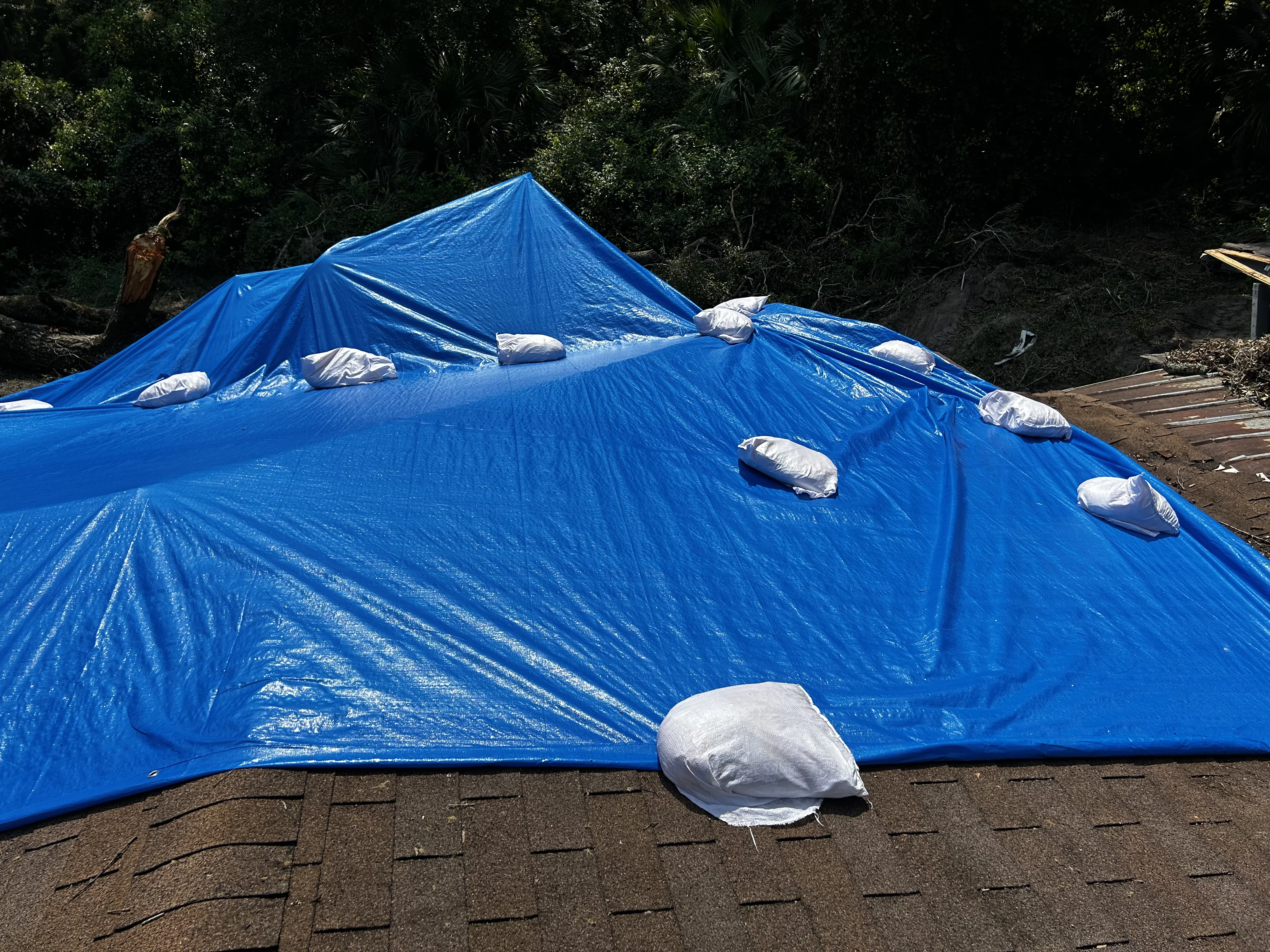 Adjuster checklist clipboard with completed roof tarping inspection items at storm damaged property