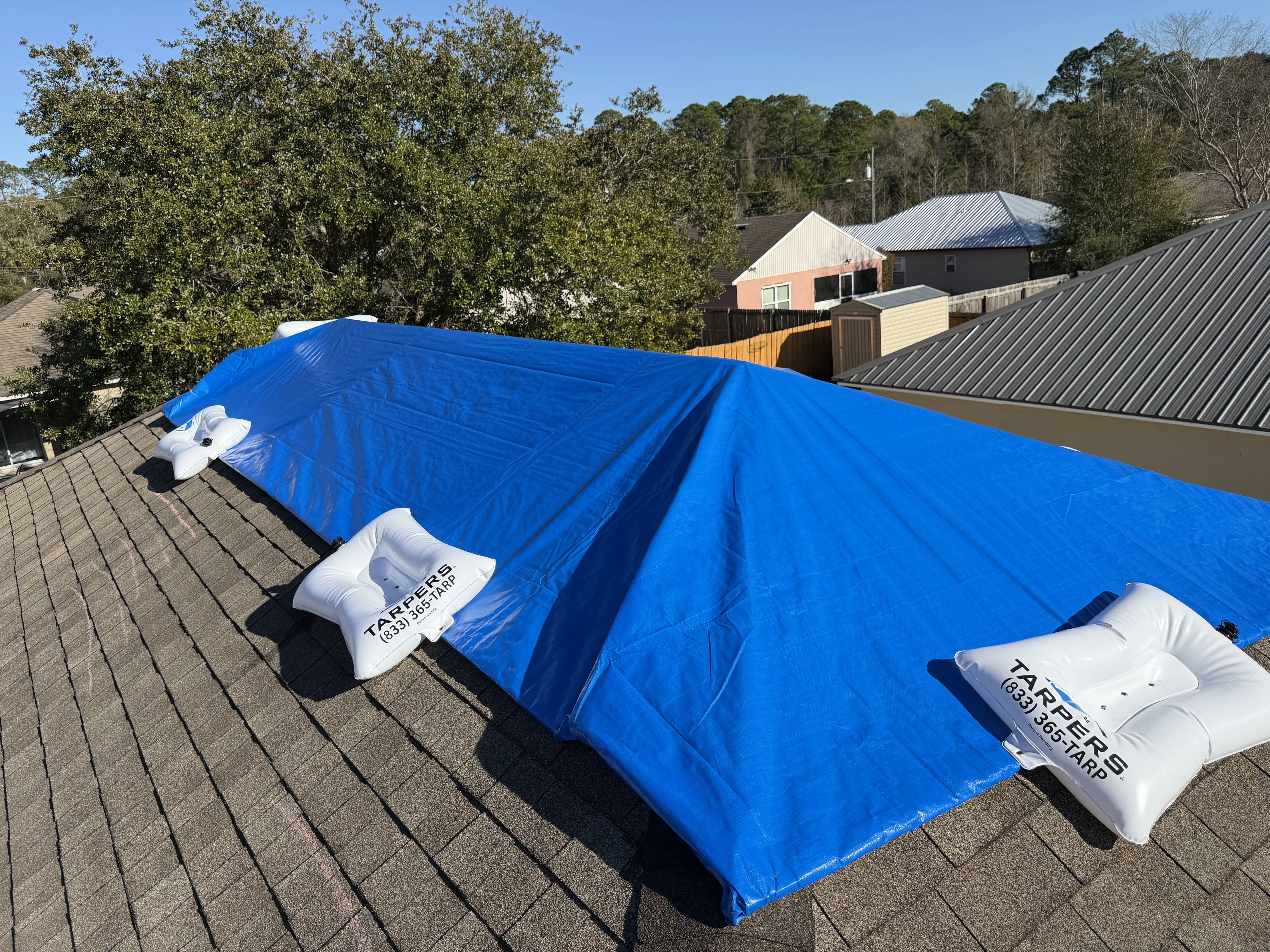 Failed emergency roof tarp blown loose after storm showing exposed roof damage and water intrusion