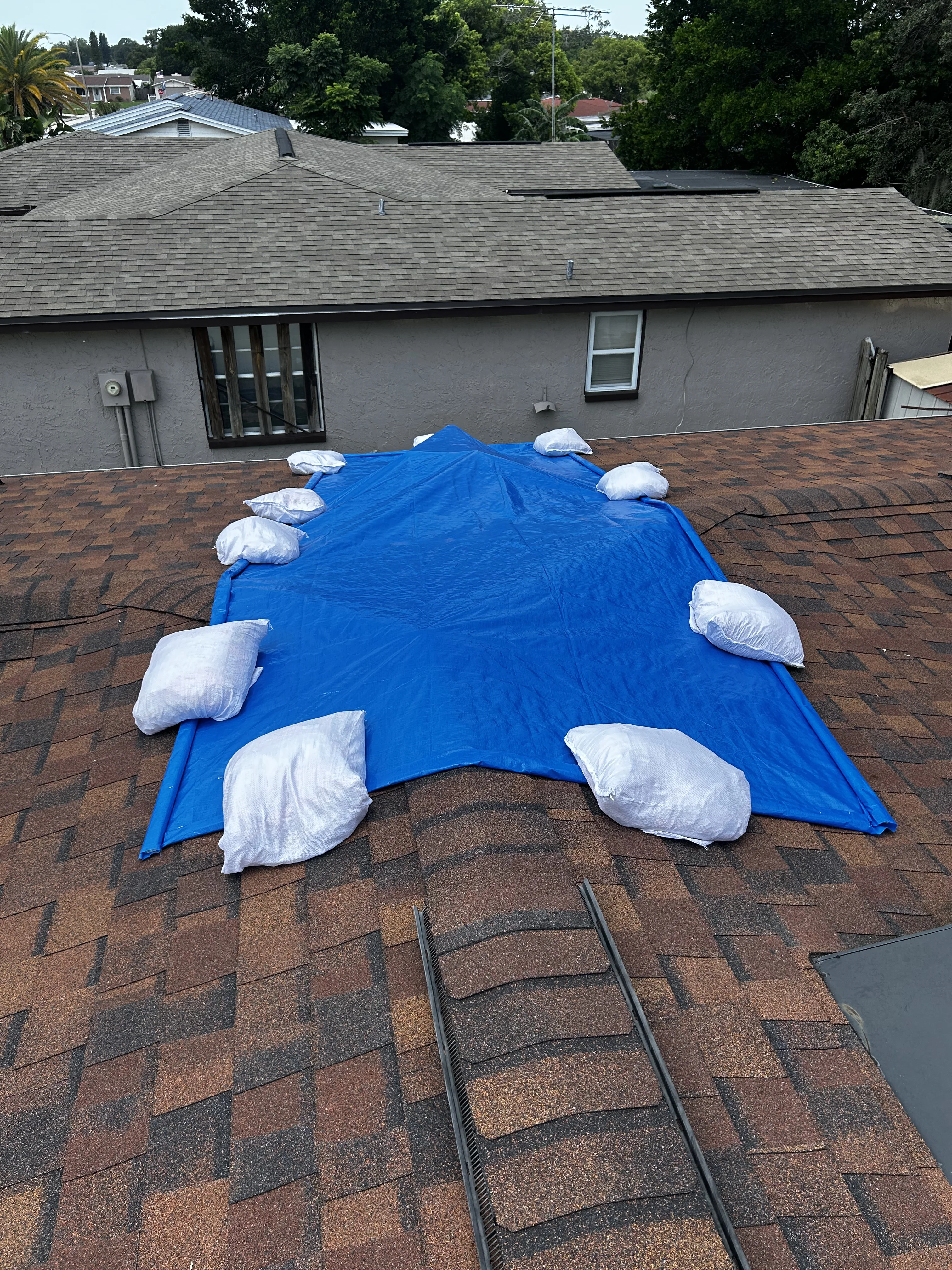 Insurance adjuster operating drone to document roof tarping installation from aerial view