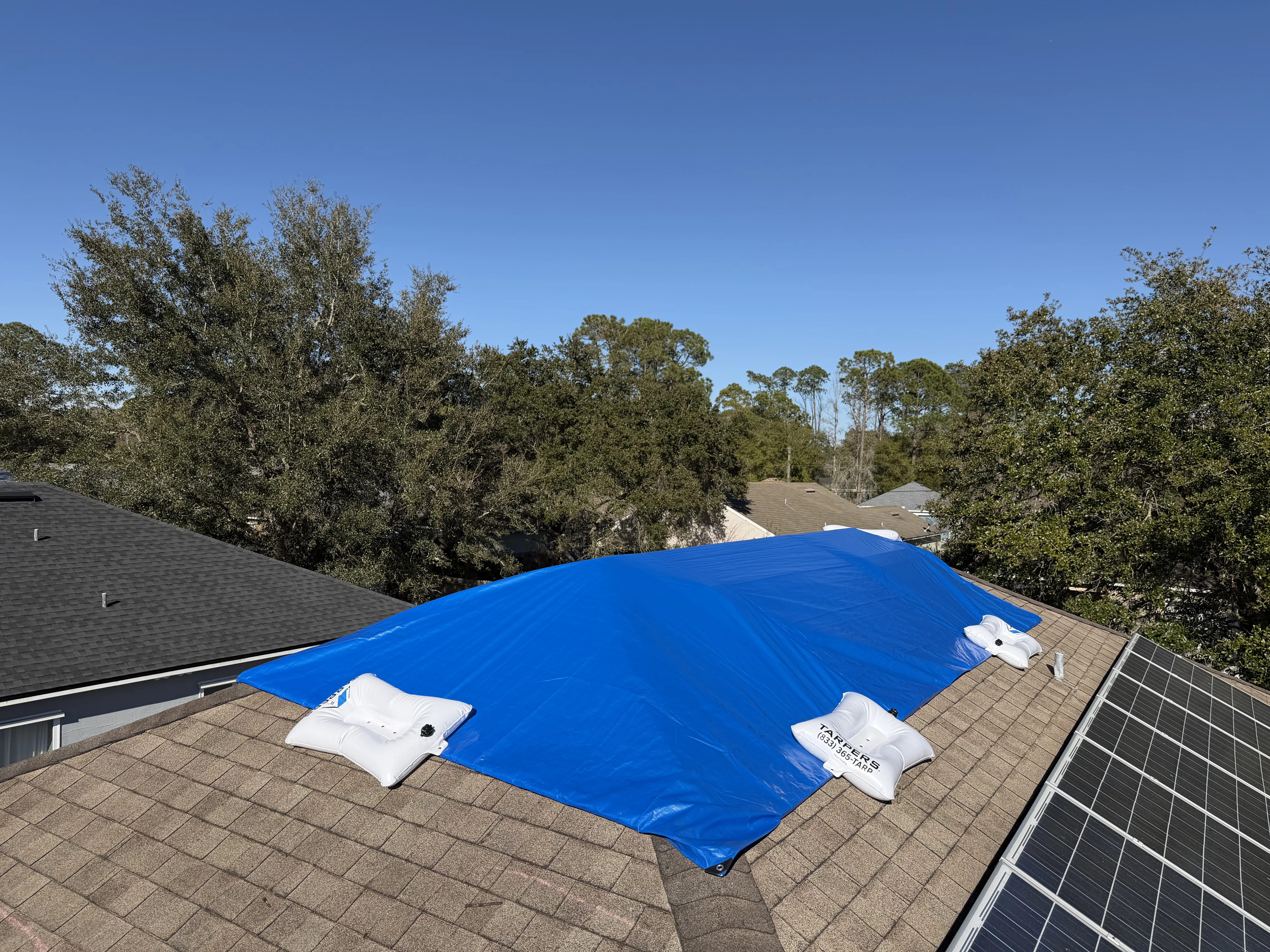 Adjuster reviewing photo documentation of emergency roof tarping on tablet at the property